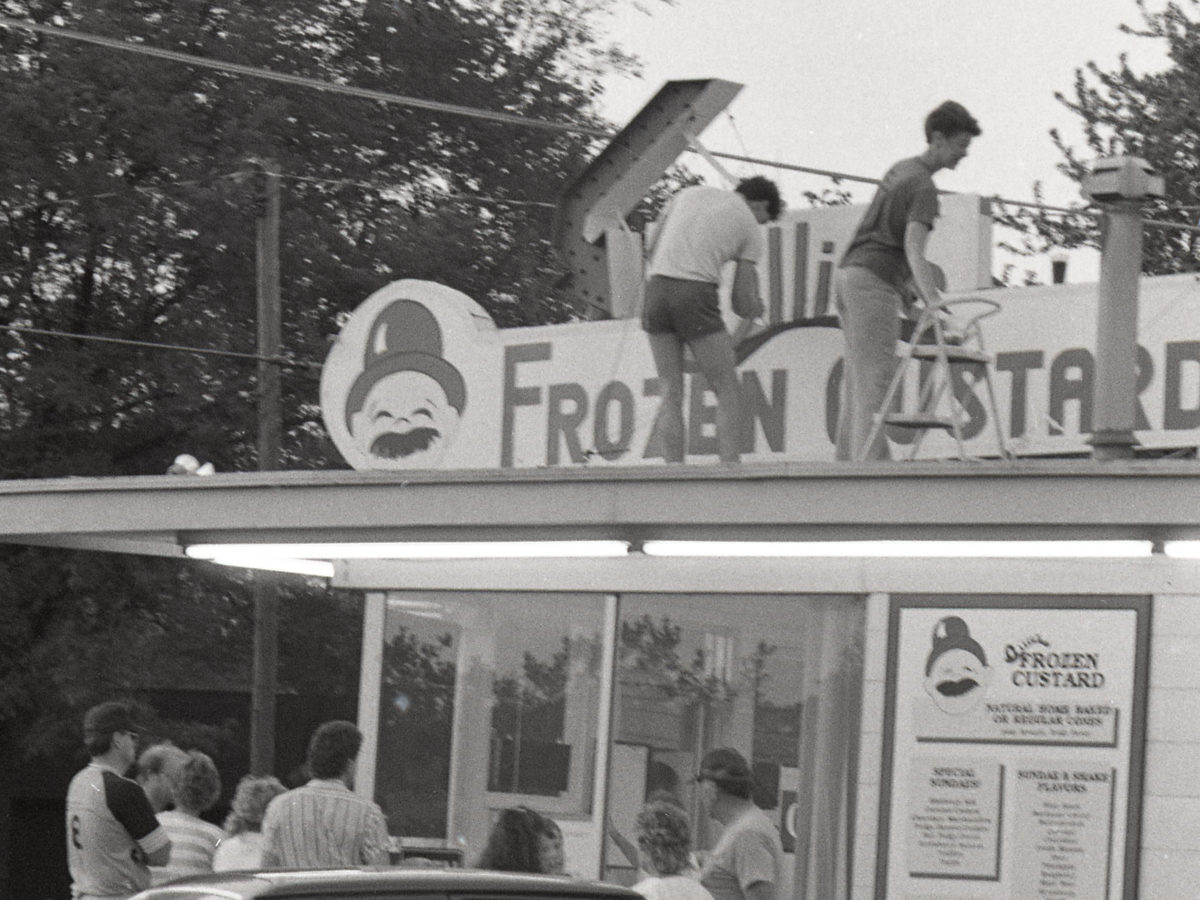 Ollie's sign and stand seen past cars in the parking lot in 1988